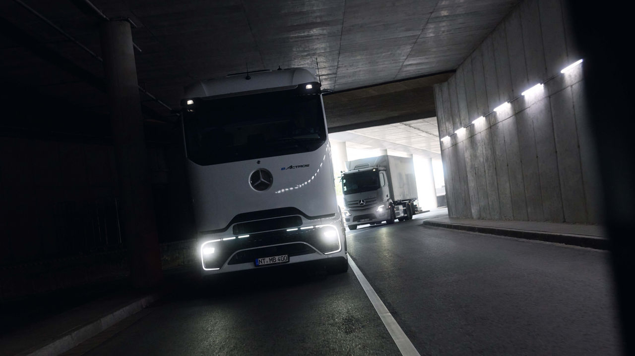 Deux eActros 400, l'un avec ProCabin et l'autre avec une cabine éprouvée, traversent un tunnel sombre avec les phares allumés. À l'extrémité du tunnel, la lumière du jour claire contraste avec l'environnement sombre.